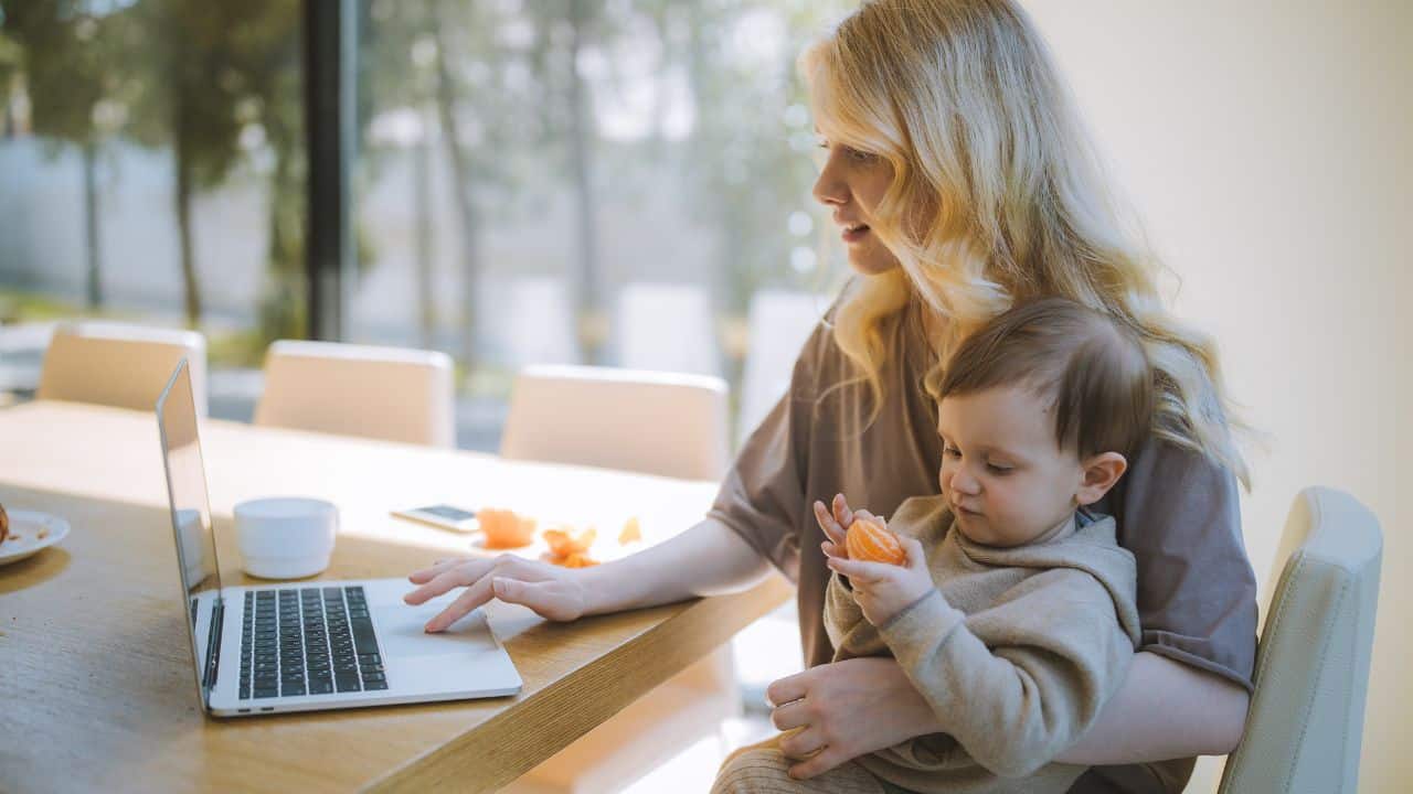 Mother typing with child and managing work-life balance